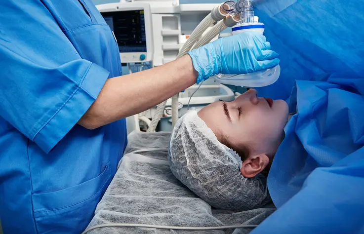 Medical professional administering anesthesia to patient before surgery.